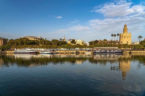On the banks of the Guadalquivir river with the historic Torre del Oro tower in Seville