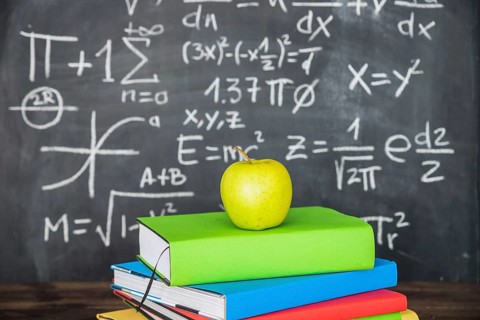 Apple books pile near chalkboard