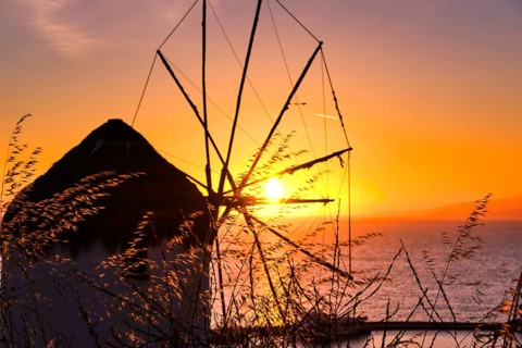 Silhouette of famous traditional Greek windmill against colorful sunset sky