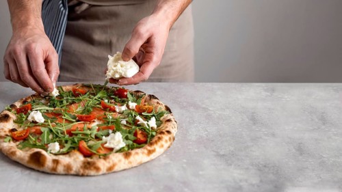 Man putting mozzarella baked pizza dough with smoked salmon slices