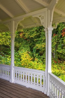 Wooden veranda with wooden floor and a white railing and beautiful autumn colours