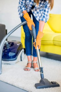 Close up woman s hand cleaning carpet with vacuum cleaner