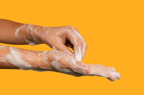 Person washing hands isolated orange