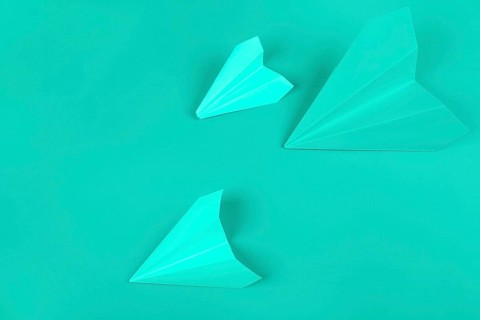 Overhead view green paper airplanes mint background
