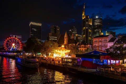 The colourful lights of the Mainfest shine in the evening. The Mainfest on the Mainkai