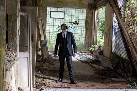 Man dressed in suit wearing VR glasses in a dilapidated office building