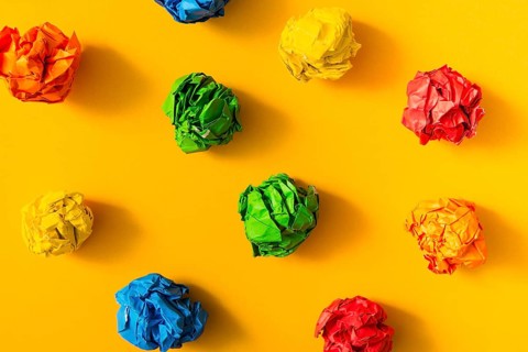 Colorful crumpled paper ball yellow background