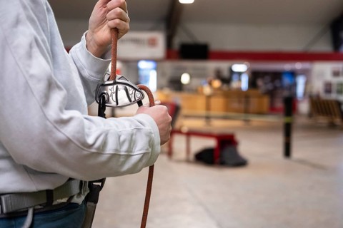 A person holding a rope for belaying in a climbing gym