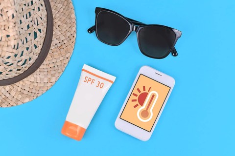 Concept for hot temperatures in summer with mobile phone showing weather forecast surrounded by sun glasses