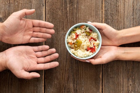 Hand giving bowl food needy person