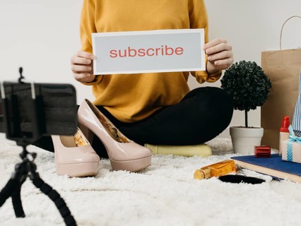 Female fashion blogger streaming home with smartphone subscribe word