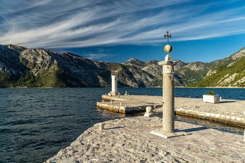 Cross and lighthouse on the artificial island of Gospa od Skrpjela near Perast on the Bay of Kotor