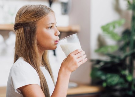 Side view girl drinking glass milk