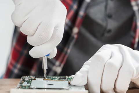 Technician repairing computer motherboard with screwdriver