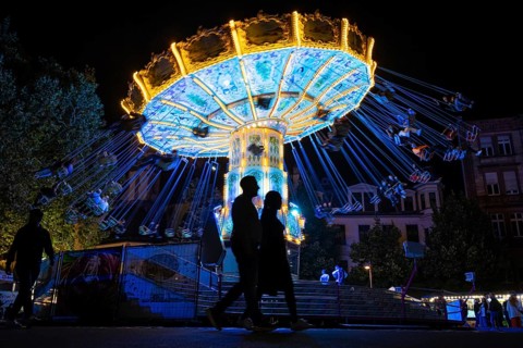 The colourful lights of the carousel at the Mainfest glow in the evening. The Mainfest on the Mainkai