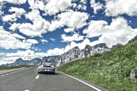 Photo with reduced dynamic range saturation HDR of view of Porsche 911 GT3 driving on mountain road above tree line pass road alpine pass mountain pass in high alps