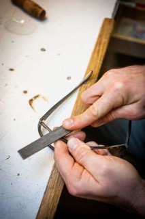 An optician files the frame of a pair of glasses with a file