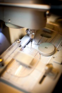 An optician drills a hole in a lens for the temple of a pair of glasses
