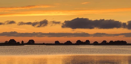 Beach houses along the Baltic Sea on the peninsula Graswarder silhouetted against sunset sky in summer