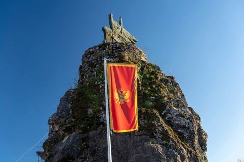 Flag of Montenegro and the Monument to the Partisans and Heroes of the Second World War in Virpazar on Lake Scutari
