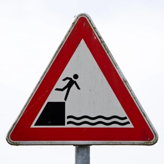 Sign warns people not to fall off the edge into the water
