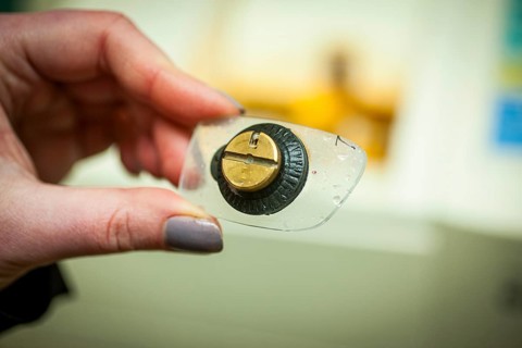 A woman holds a cut spectacle lens in her hand