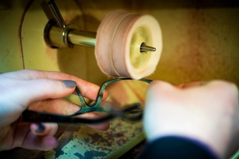 An optician polishes a pair of glasses