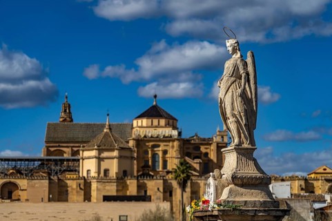 Statue of the Archangel Raphael on the Roman Bridge and the Mezquita in Cordoba