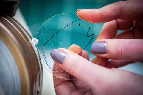 A woman grinds a lens at an optician's shop