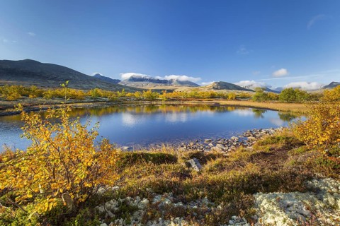 The mountains Hogronden and Digerronden reflected in water of lake in autumn