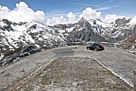Photo with reduced dynamic range saturation HDR of view of Porsche 911 993 driving into hairpin bend 5 of historic old Grossglockner High Alpine Road Grossglockner-Hochalpenstrasse with cobblestones m...