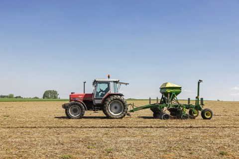 Tractor pulling John Deere 750A no-till seed drill working on farmland