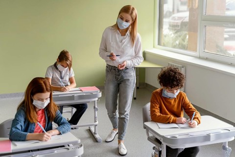 Children with medical masks learning school with teacher