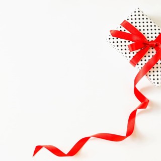 Elevated view gift tied with red ribbon white surface