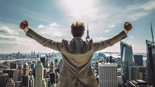 Excited businessman celebrates with his fists in the air with the city in the background