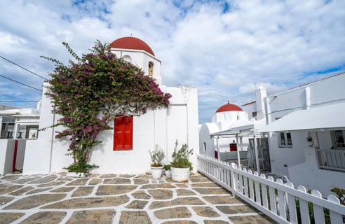 White Greek Orthodox Church of St Nicholas with red roof and bougainvillea