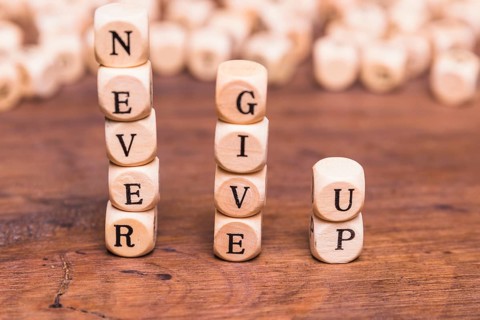 Stacked wooden blocks with word never give up wooden desk