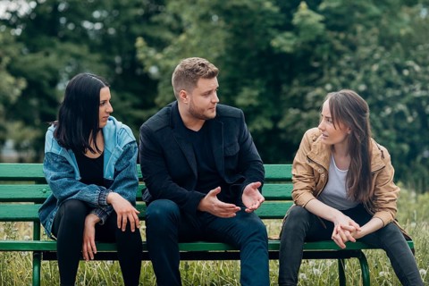 Conflicting people sitting bench talking