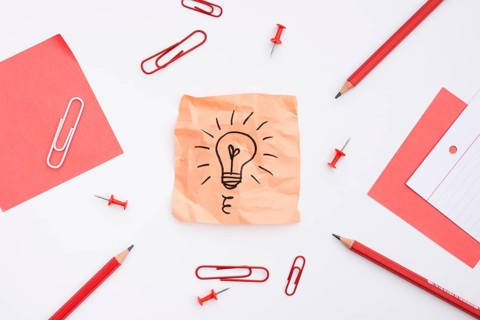 Sticky note with drawn light bulb office supplies white background