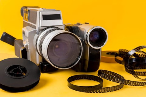 Modern camera film reel film strips yellow background