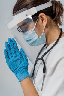 Side view female doctor with medical mask face shield praying