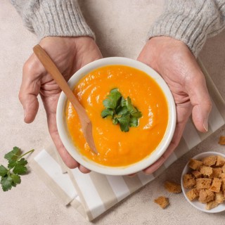 Close up hands holding cream soup bowl