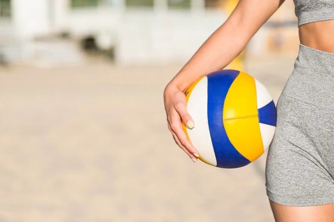 Front view female volleyball player beach holding ball with copy space