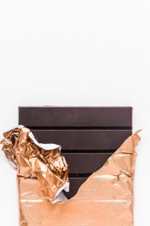 Delicious chocolate bar wrapped golden foil white background