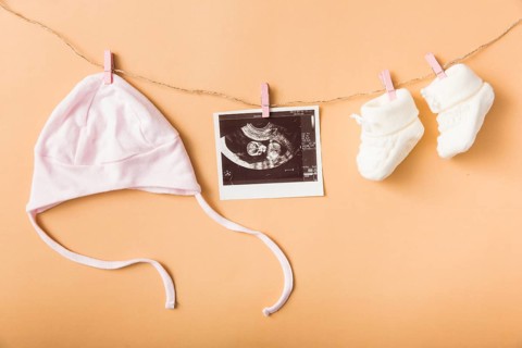 Baby s cap ultrasound picture pair woolen shoes hanging clothesline against orange backdrop