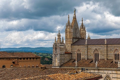 Dark clouds over the Siena Cathedral with its black and white striped marble facade