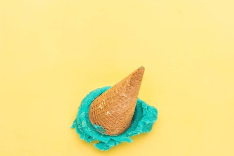 Blue ice cream cone falling yellow background