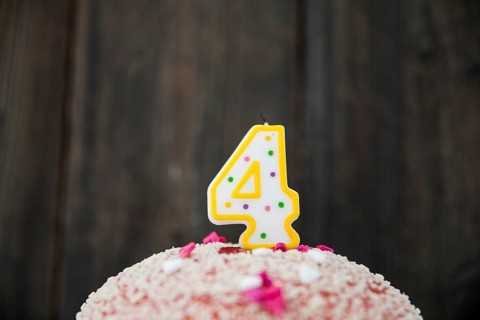 Number 4 candle birthday cake against blue wooden background