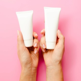 Close up hands holding cream bottles