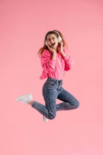 Portrait happy woman jumping listening music